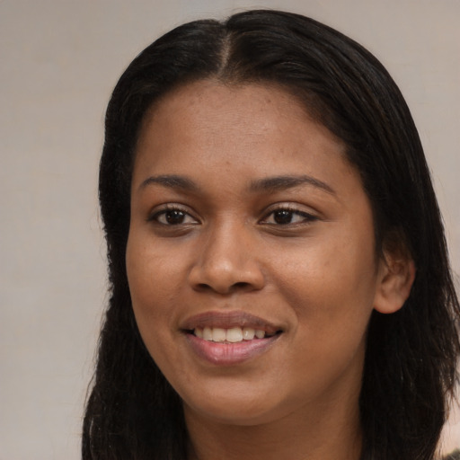 Joyful black young-adult female with long  brown hair and brown eyes