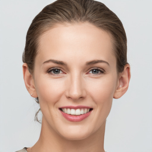 Joyful white young-adult female with medium  brown hair and grey eyes