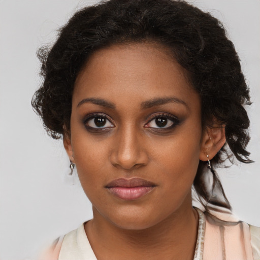 Joyful black young-adult female with long  brown hair and brown eyes