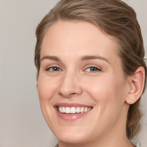 Joyful white young-adult female with medium  brown hair and grey eyes