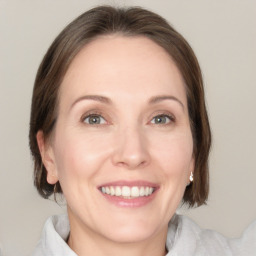 Joyful white adult female with medium  brown hair and green eyes