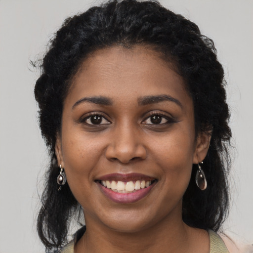 Joyful black young-adult female with long  black hair and brown eyes
