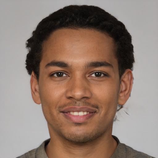 Joyful black young-adult male with short  brown hair and brown eyes