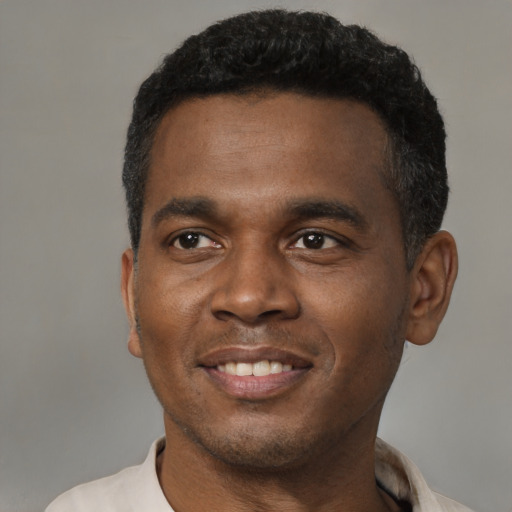 Joyful black young-adult male with short  brown hair and brown eyes