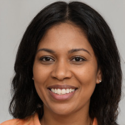 Joyful black young-adult female with long  brown hair and brown eyes