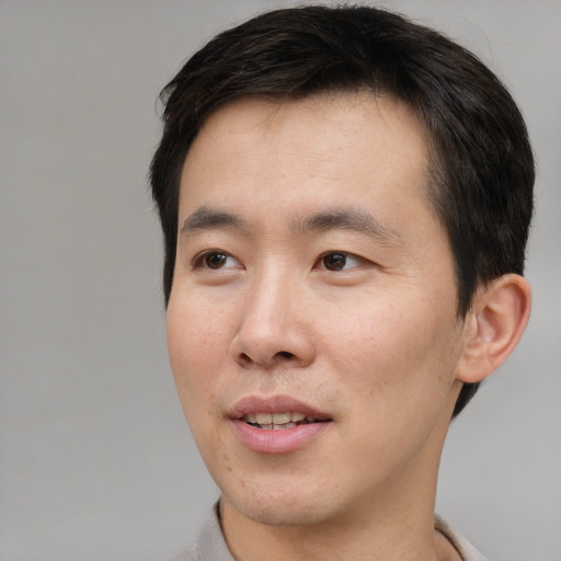 Joyful asian young-adult male with short  brown hair and brown eyes