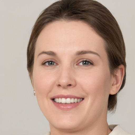 Joyful white young-adult female with medium  brown hair and grey eyes