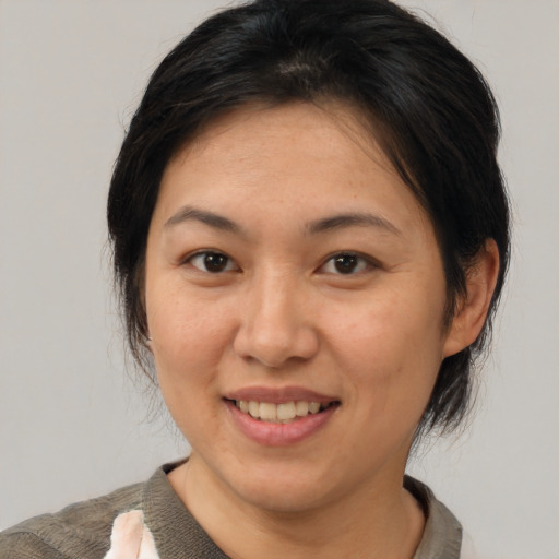 Joyful asian adult female with medium  brown hair and brown eyes