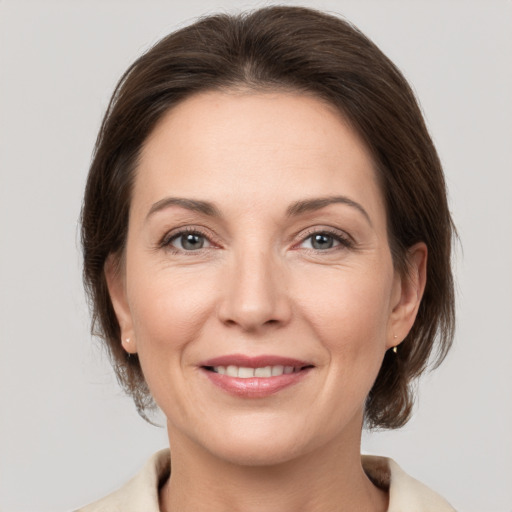 Joyful white adult female with medium  brown hair and grey eyes