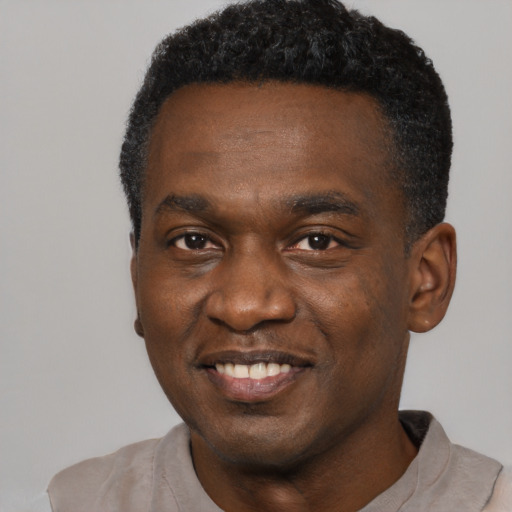 Joyful black young-adult male with short  black hair and brown eyes