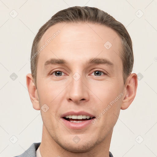 Joyful white young-adult male with short  brown hair and grey eyes