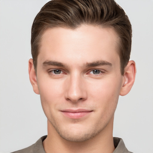 Joyful white young-adult male with short  brown hair and grey eyes