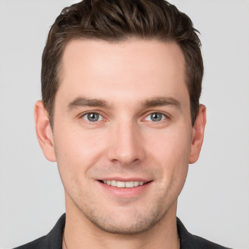 Joyful white young-adult male with short  brown hair and grey eyes