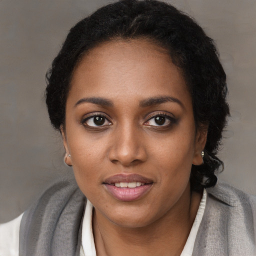 Joyful black young-adult female with short  black hair and brown eyes