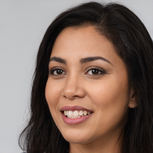 Joyful latino young-adult female with long  brown hair and brown eyes