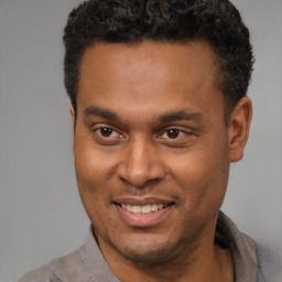 Joyful black young-adult male with short  brown hair and brown eyes