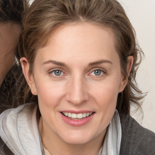 Joyful white young-adult female with medium  brown hair and grey eyes