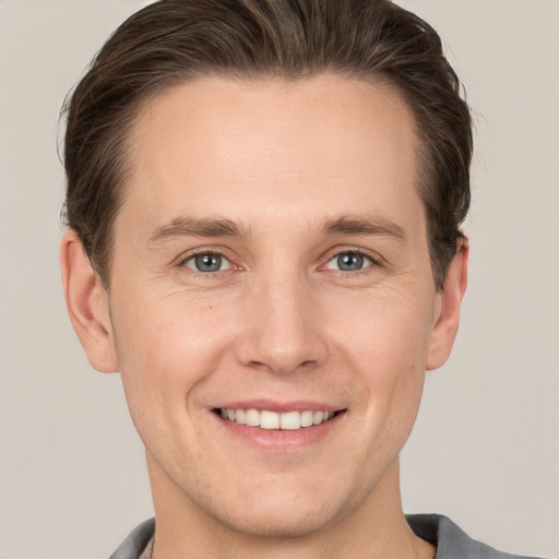 Joyful white young-adult male with short  brown hair and grey eyes