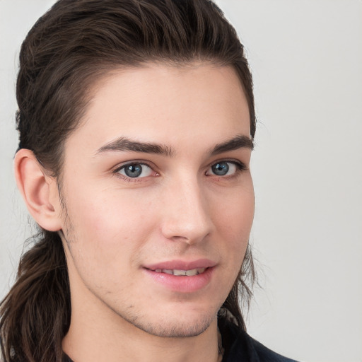 Joyful white young-adult male with long  brown hair and brown eyes