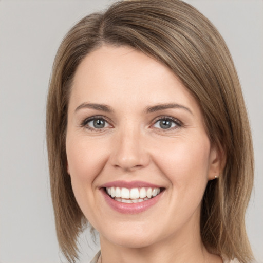 Joyful white young-adult female with medium  brown hair and grey eyes