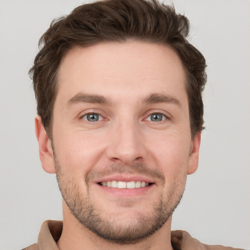 Joyful white young-adult male with short  brown hair and grey eyes