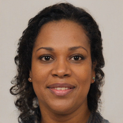 Joyful black adult female with long  brown hair and brown eyes