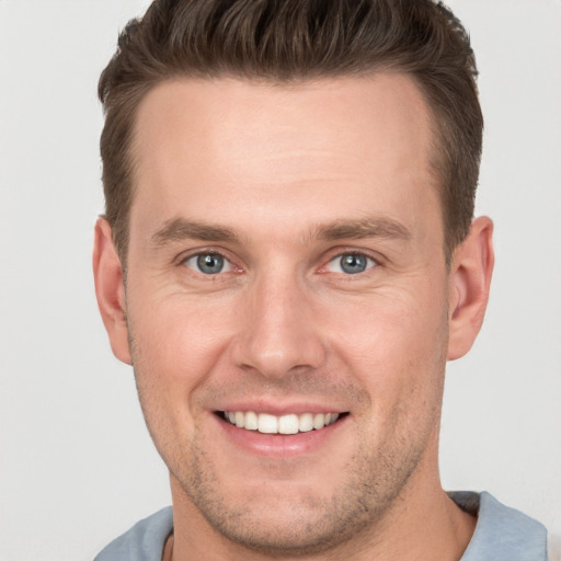 Joyful white young-adult male with short  brown hair and grey eyes