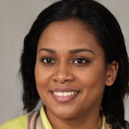 Joyful black young-adult female with long  brown hair and brown eyes