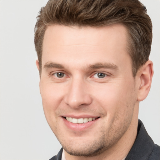 Joyful white young-adult male with short  brown hair and grey eyes