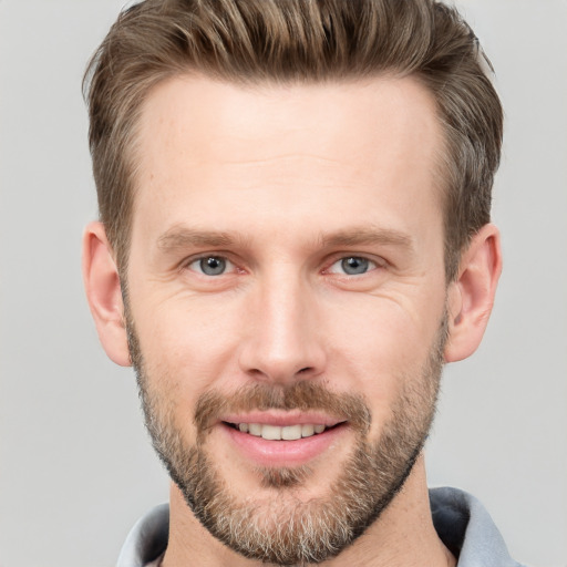 Joyful white young-adult male with short  brown hair and grey eyes