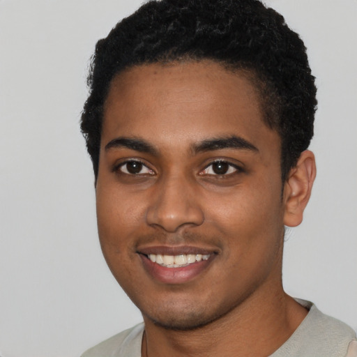 Joyful black young-adult male with short  black hair and brown eyes