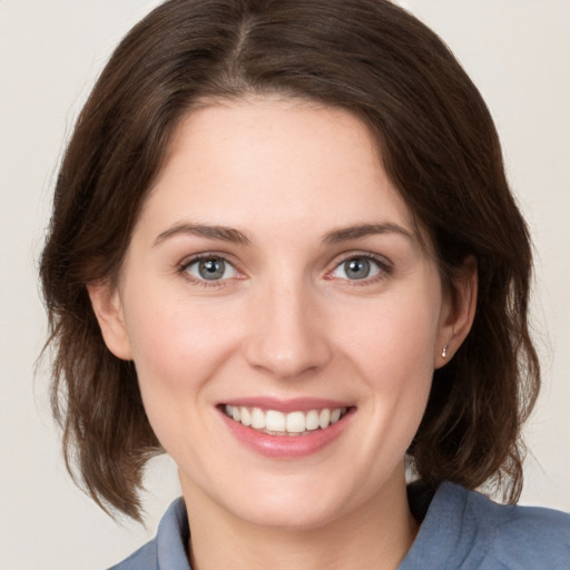 Joyful white young-adult female with medium  brown hair and grey eyes