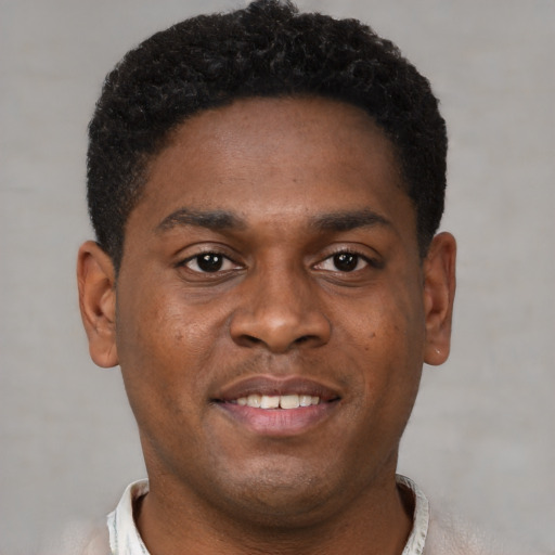 Joyful black young-adult male with short  brown hair and brown eyes