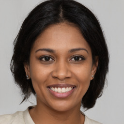 Joyful black young-adult female with medium  brown hair and brown eyes