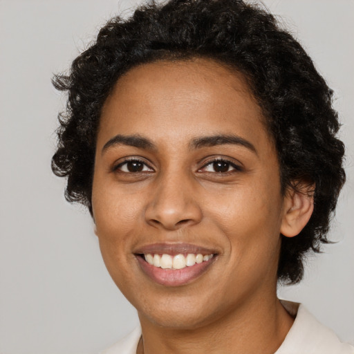 Joyful black young-adult female with short  black hair and brown eyes