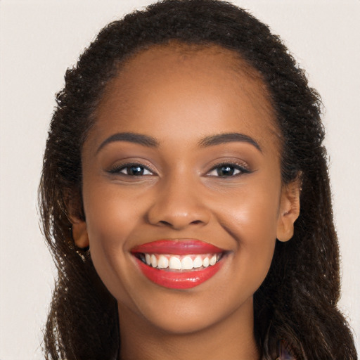 Joyful black young-adult female with long  brown hair and brown eyes