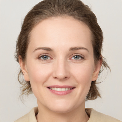 Joyful white young-adult female with medium  brown hair and grey eyes