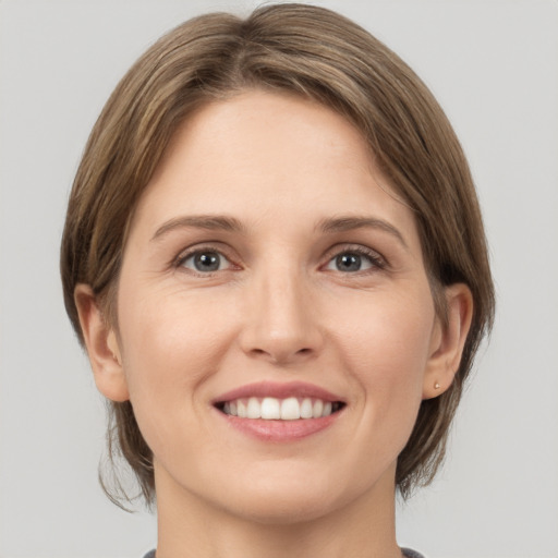 Joyful white young-adult female with medium  brown hair and grey eyes