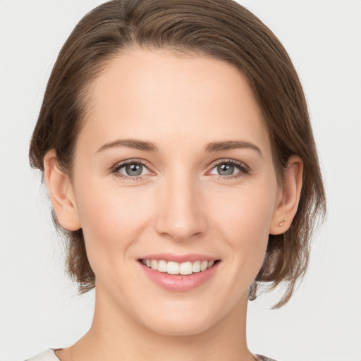 Joyful white young-adult female with medium  brown hair and grey eyes