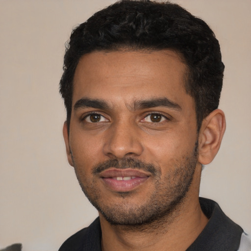 Joyful black young-adult male with short  black hair and brown eyes