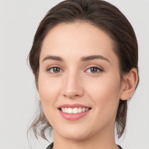 Joyful white young-adult female with medium  brown hair and grey eyes