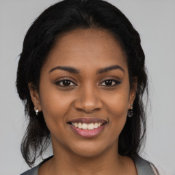 Joyful black young-adult female with long  brown hair and brown eyes