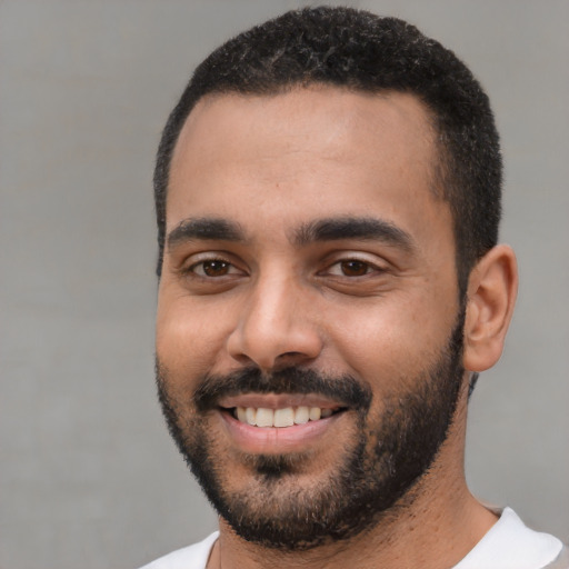 Joyful black young-adult male with short  black hair and brown eyes
