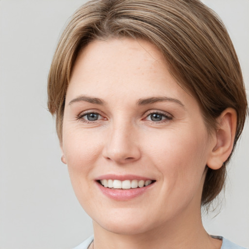 Joyful white young-adult female with medium  brown hair and grey eyes