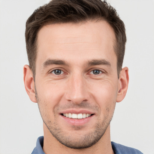 Joyful white young-adult male with short  brown hair and grey eyes