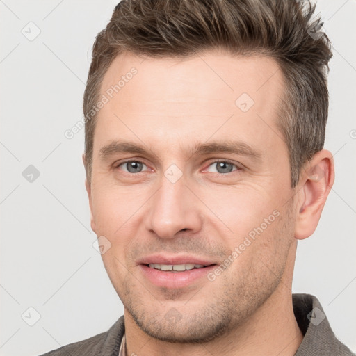 Joyful white young-adult male with short  brown hair and grey eyes