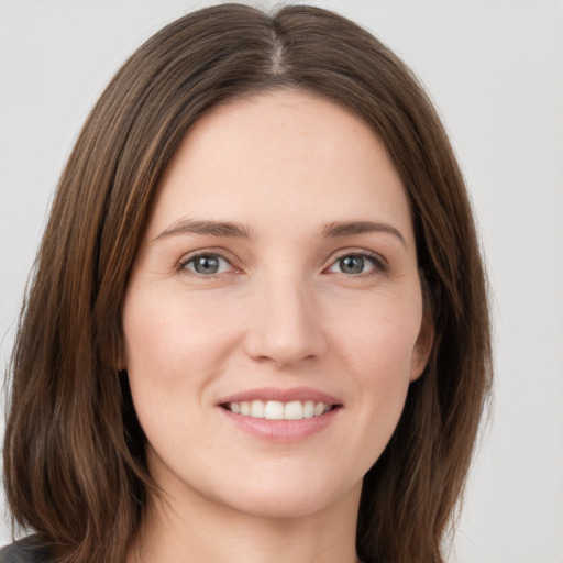 Joyful white young-adult female with long  brown hair and grey eyes