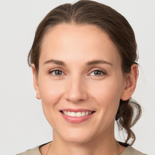 Joyful white young-adult female with medium  brown hair and grey eyes