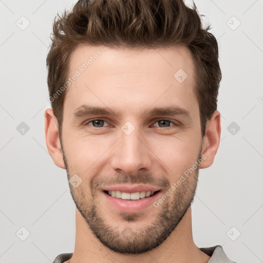 Joyful white young-adult male with short  brown hair and grey eyes