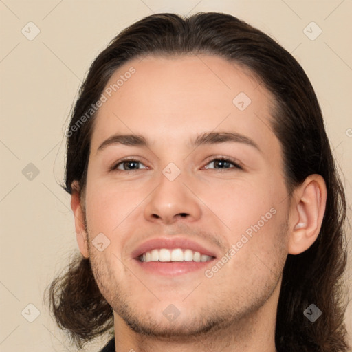 Joyful white young-adult male with long  brown hair and brown eyes